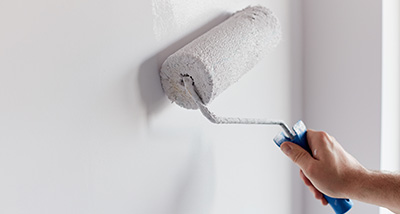 a person using a paint rollar to paint a wall white