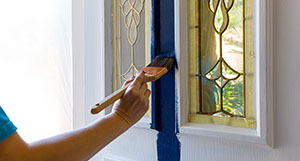 a person using a paint brush to paint a door blue