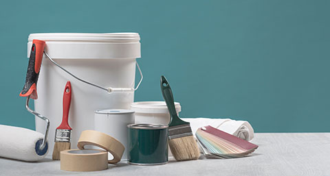a number of different painting tools and colour swatch next to a paint bucket