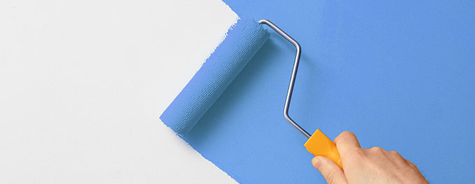 a person using a paint roller to paint a white wall sky blu