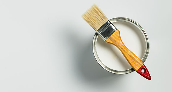 a paintbrush on top of a bucket of white paint
